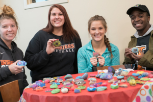four students holding up their painted hope rocks and smiling
